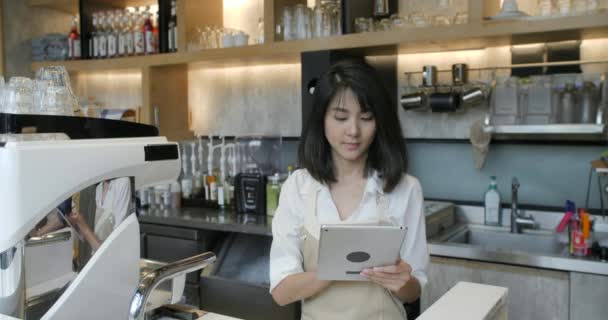 Giovane asiatico barista utilizzando tablet computer durante una pausa sul lavoro nella caffetteria — Video Stock