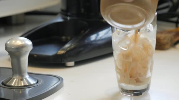 Barista gießt frischen Kaffee in ein Glas Eis — Stockvideo