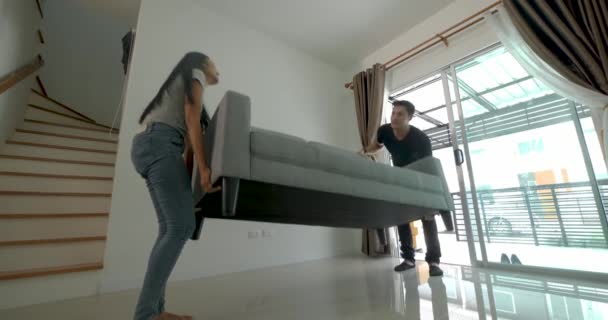 glückliches junges asiatisches Paar beim Sofa-Umzug in sein neues Haus