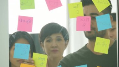 İşadamı yazmak ve grafikler cam tahta üzerinde tartışmak