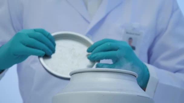 Γκρο πλαν ενός επιστήμονα της ιατρικής έρευνας βγάζει γυάλινο μπουκάλι με πειραματική λύση υγρού από ένα εμπορευματοκιβώτιο κρυογόνος αζώτου σε ένα εργαστήριο έρευνας επιστήμης — Αρχείο Βίντεο