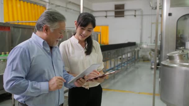 Fabrikschef med unga kvinnliga bistånd diskuterar verksamheten. — Stockvideo