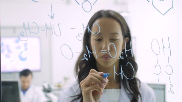 Medische onderzoekers wetenschappelijke formule schrijft op een whiteboard glas. — Stockvideo