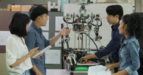 Mladí elektronika inženýr týmu, spolupráce na výstavbě robota v dílně. — Stock video