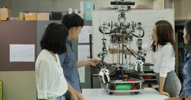 Equipo joven de ingenieros electrónicos colaborando en la construcción de robots en el taller . — Vídeo de stock