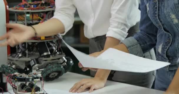 Молодая команда инженеров-электроников, работающая над созданием робота в цехе . — стоковое видео