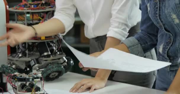 Equipo joven de ingenieros electrónicos colaborando en la construcción de robots en el taller . — Vídeo de stock