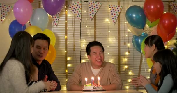 Feliz asiático macho sentado en mesa celebra su cumpleaños con un pastel . — Vídeo de stock