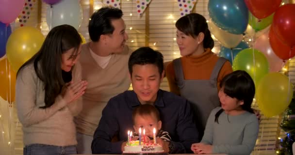 Pai e filho sentados à mesa e soprando velas no bolo de aniversário . — Vídeo de Stock
