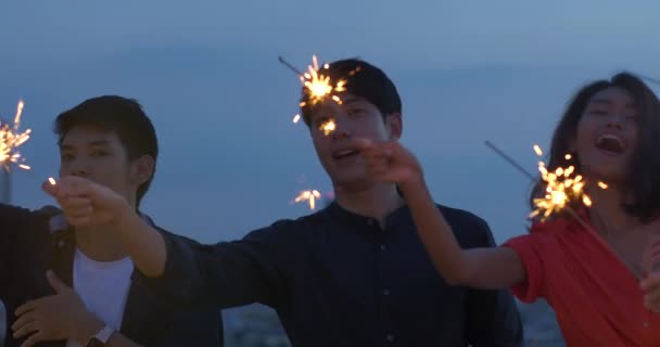 Happy group of young friends enjoy and play sparkler at roof top party at evening sunset. Holiday celebration festive party. Teenage lifestyle party. — Stock Video