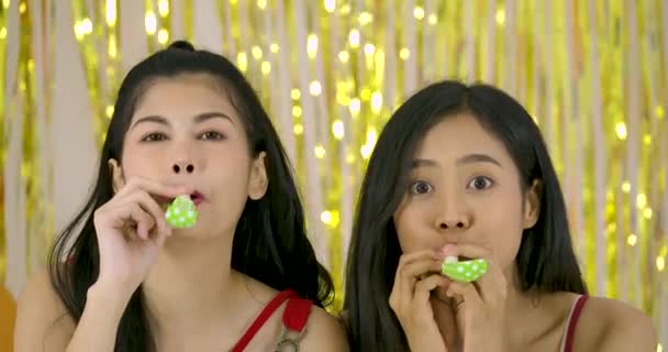 Dos chicas divirtiéndose con soplador de cuerno de fiesta en cámara lenta . — Vídeo de stock