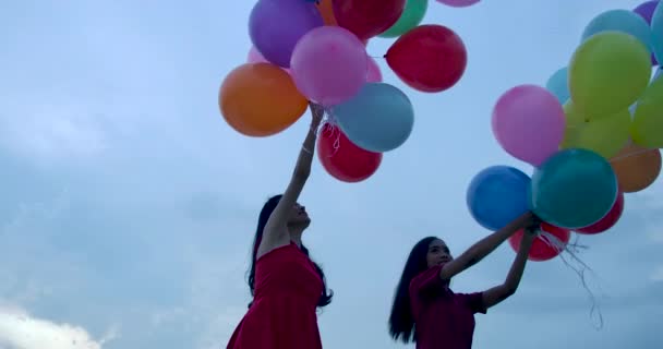 Две девушки держат воздушный шар на фоне неба . — стоковое видео