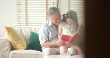 Asya kıdemli dedesi ile birlikte evde kitap okurken küçük torunu.