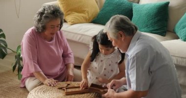 Küçük bir kız ile birlikte evde oynarken Asya kıdemli çift.