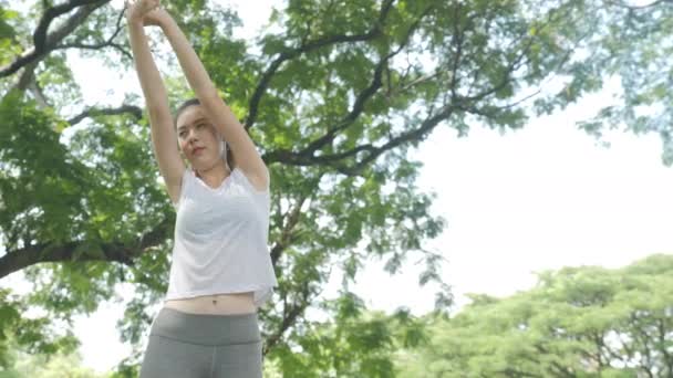 Atletische jonge Aziatische vrouw warming-up en stretching voor training bij zonsopgang in een Park. — Stockvideo