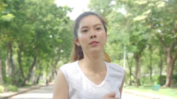Молодая привлекательная женщина бегает в зеленом городском парке, тренируясь на открытом воздухе фитнес-трекер носимые технологии . — стоковое видео