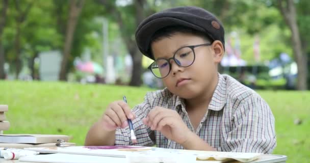 Pequeño artista joven pintando en el parque . — Vídeos de Stock