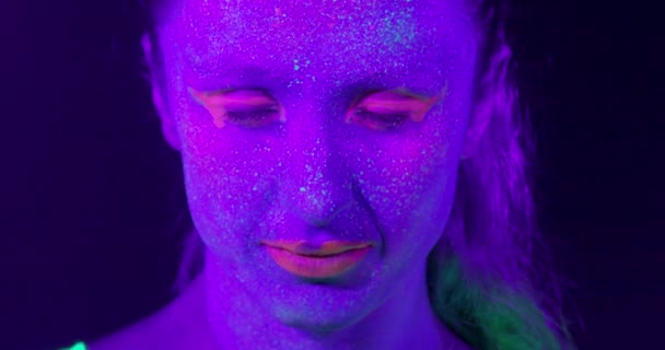 Closeup vrouw gezicht met fluorescerende make-up, creatieve make-up ziet er geweldig uit voor nachtclubs. — Stockvideo
