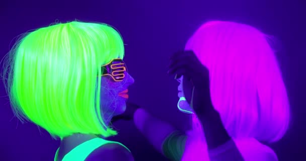 Motin lent de belles femmes sexy avec du maquillage fluorescent et des vêtements dansant au néon . — Video