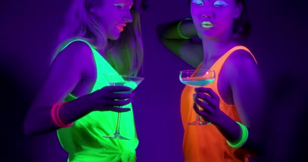 Slow motin of beautiful sexy women with fluorescent make-up and clothing dancing in neon light. — Stock Video