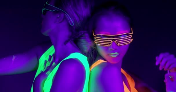 Motim lento de mulheres sexy bonitas com maquiagem fluorescente e roupas dançando em luz de néon . — Vídeo de Stock