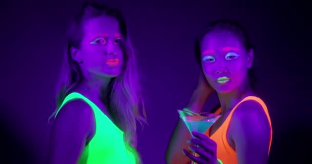 Медленный мотин красивых сексуальных женщин с флуоресцентным макияжем и одеждой, танцующих в неоновом свете . — стоковое видео