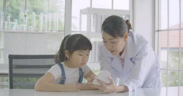 Öğrenme anatomi dersi çene modeli ile insan iskeleti hakkında küçük Asya öğrenci kız. — Stok video