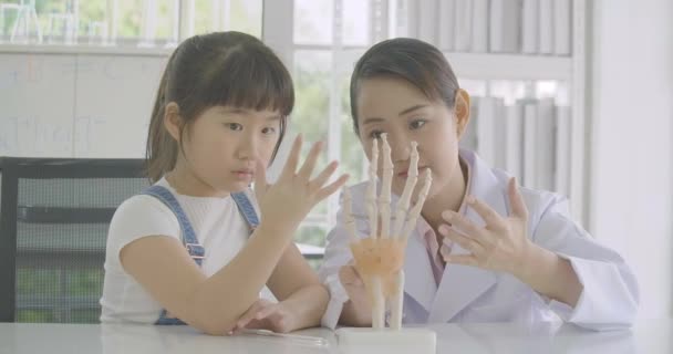 在解剖学课上学习人体骨骼的亚洲小学生女孩. — 图库视频影像