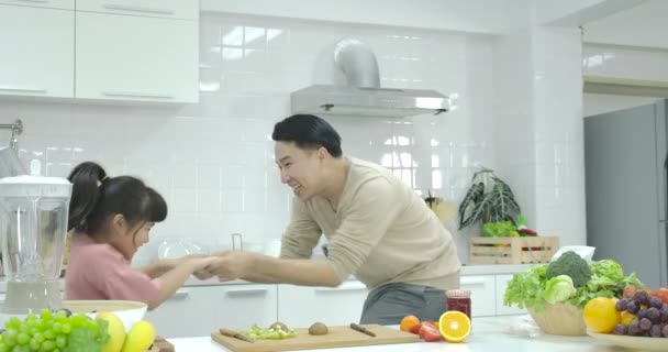 Glücklich junge freudige asiatische Vater und Tochter tanzen, während Kochen in der Küche zu Hause — Stockvideo