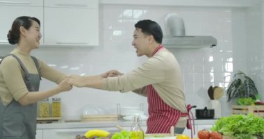 Mutlu genç neşeli Asya çift evde mutfakta yemek yaparken dans eğlenceli