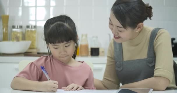 Mor och dotter gör en skola hemuppgift. Mamma hjälper till att ta itu med det — Stockvideo