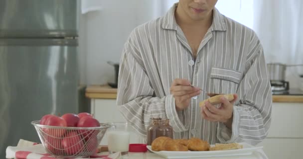 Attraktiv ung asiatiska gay par äter frukost i köket. Man matlagning frukost för honom pojkvän med attraktivt leende. — Stockvideo