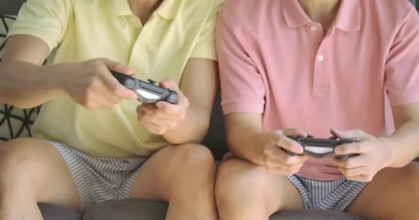 Конкурентная молодая азиатская гей-пара толкает и толкает друг друга, когда они играют в видеоигру дома — стоковое видео