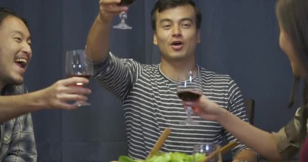 Groupe d'amis toastant et buvant du vin pendant le dîner 