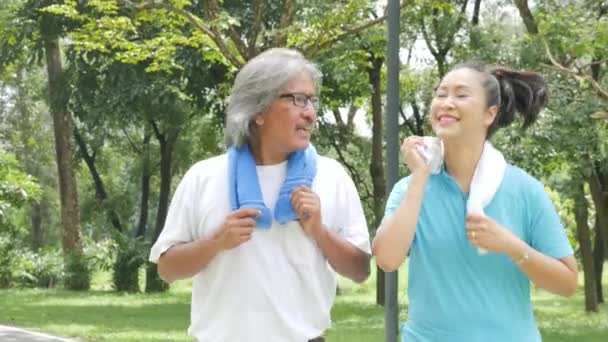 Asian senior couple jogging in sunny garden — Stock Video