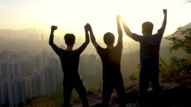 Dağın tepesinde zaferi kutlamak için sevindirici ve ellerini kaldırarak insan silüeti.