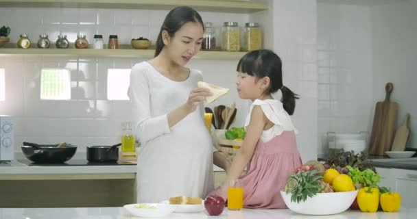 Sonriendo madre embarazada y la hija disfruta de estar en la cocina juntos — Vídeo de stock