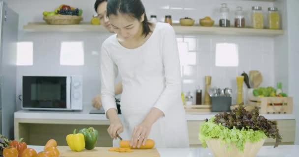 Mujer embarazada y su marido preparando alimentos saludables juntos en la cocina en casa . — Vídeos de Stock