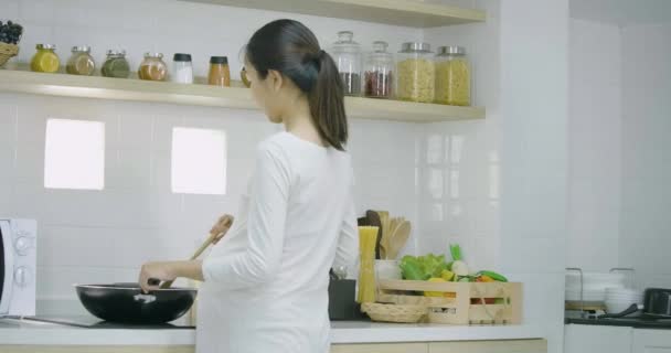 임신한 여자와 함께 부엌에 있는 가정에서 건강 한 음식을 준비 하는 그녀의 남편. — 비디오