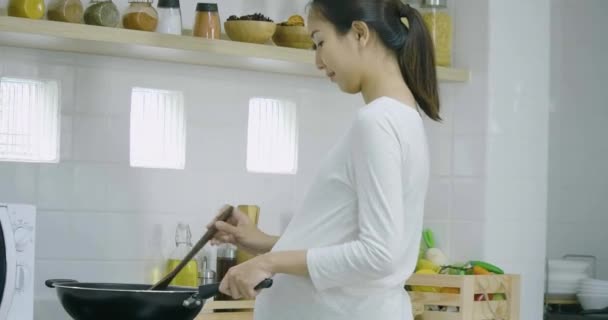 Έγκυος γυναίκα και ο σύζυγός της προετοιμασία υγιεινά τρόφιμα μαζί στην κουζίνα στο σπίτι. — Αρχείο Βίντεο