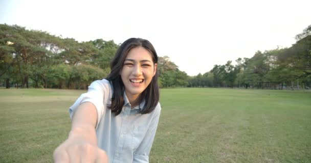 Junge attraktive asiatische Frau zieht ihren Freund bei Sonnenuntergang durch einen Sommerpark. — Stockvideo