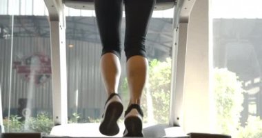 Spor salonundaki koşu bandında koşan Asyalı kadın görüntüsü. Yavaş Hareket.