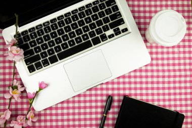 Düz yatıyordu, en iyi görünümü ofis masası. Dizüstü bilgisayar, kahve, Not defteri, kalem ve pembe çiçek ile çalışma alanı