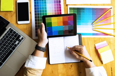 Grafik tasarımcıları, tasarım fikirleri için renk çubuğu örneğinden, grafik tasarımcıların yaratıcı tasarımlarından renk seçmek için tableti kullanır..