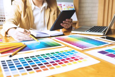 Grafik tasarımcıları, tasarım fikirleri için renk çubuğu örneğinden, grafik tasarımcıların yaratıcı tasarımlarından renk seçmek için tableti kullanır..