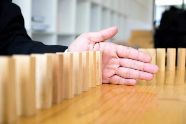 Business hand stops domino continuous overturned meaning that hindered business failure. Stop over this business failure concept.