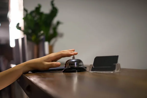 Close up women call hotel reception on counter desk with finger push a bell in lobby hotel. hotel concept.