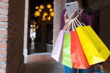 Alışveriş çantası tutarak ve smartphone için alışveriş online, alışveriş kavramı kullanarak kadın.