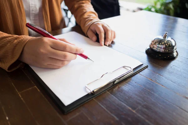 Primer plano de las mujeres que ponen la firma y llenar formulario en el hotel r —  Fotos de Stock