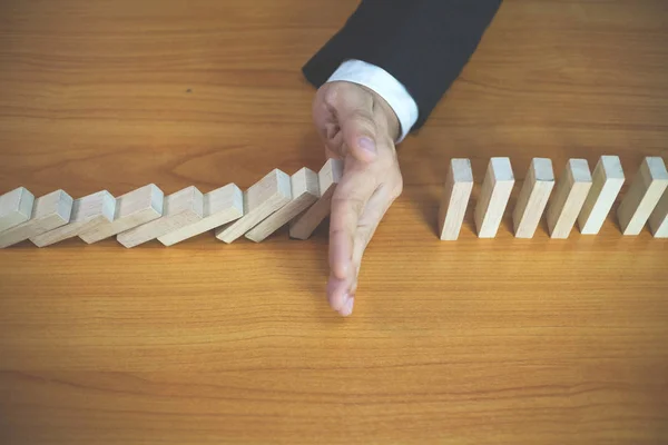 Businessman hand stops domino continuous overturned meaning that